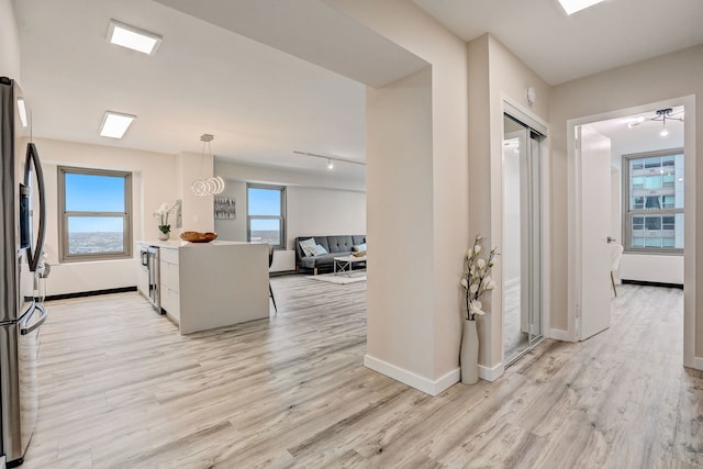 hall with plenty of natural light and light hardwood / wood-style floors