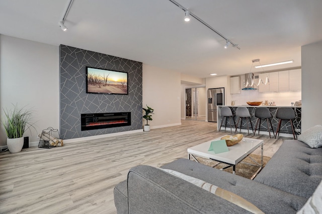 living room featuring a fireplace, light hardwood / wood-style floors, and track lighting