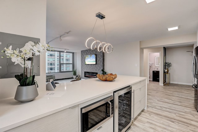 kitchen featuring pendant lighting, wine cooler, a fireplace, appliances with stainless steel finishes, and a chandelier