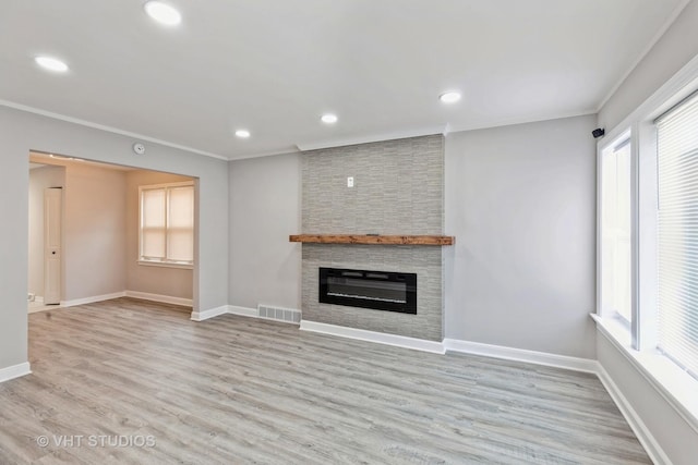 unfurnished living room with light wood-type flooring, crown molding, and a stone fireplace