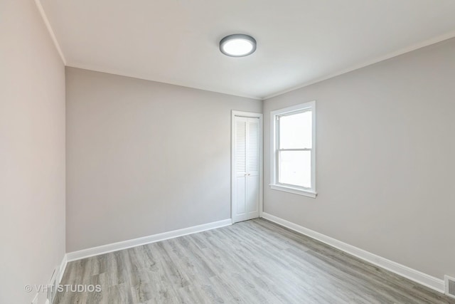 spare room with ornamental molding and light hardwood / wood-style flooring