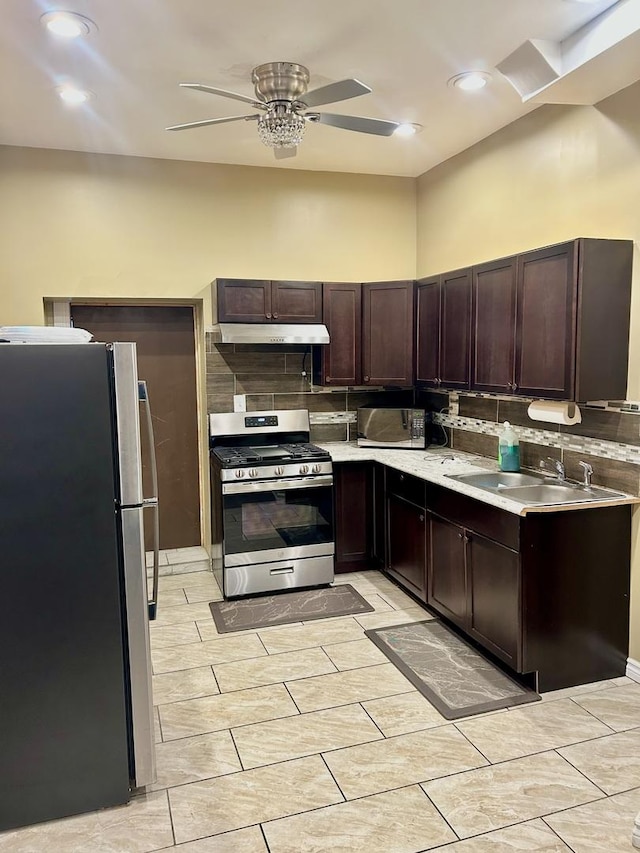 kitchen featuring decorative backsplash, dark brown cabinets, stainless steel appliances, ceiling fan, and sink