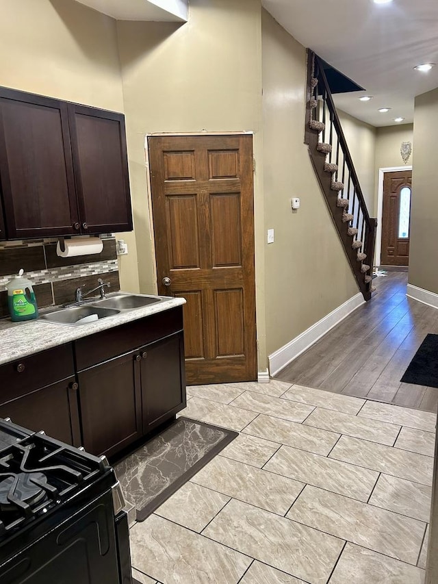 kitchen with black stove, dark brown cabinetry, tasteful backsplash, and sink