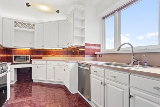 kitchen with dark tile patterned flooring, white cabinetry, sink, and appliances with stainless steel finishes