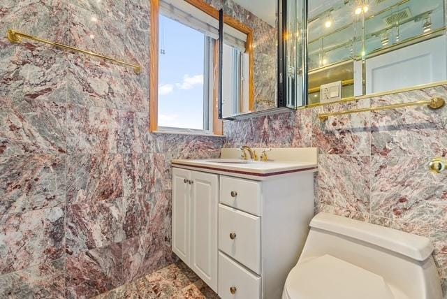 bathroom with vanity, toilet, and tile walls