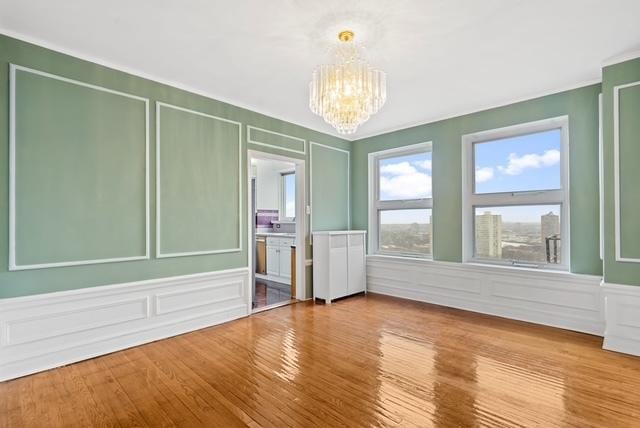 spare room featuring wood-type flooring and a chandelier