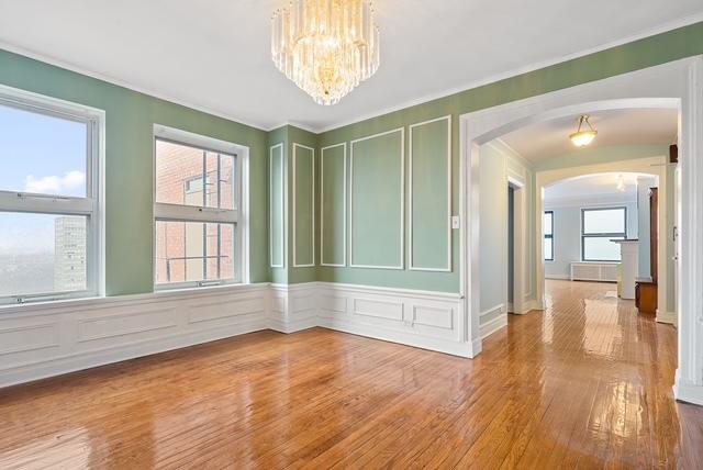 unfurnished room featuring hardwood / wood-style flooring, plenty of natural light, and a notable chandelier