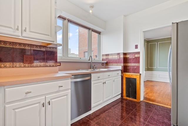 kitchen with appliances with stainless steel finishes, white cabinetry, dark tile patterned flooring, and sink