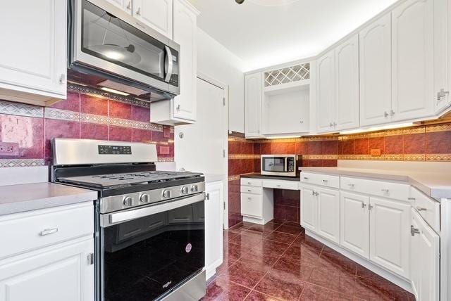 kitchen with white cabinets, dark tile patterned floors, stainless steel appliances, and tasteful backsplash