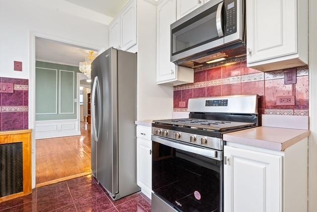 kitchen with white cabinetry, stainless steel appliances, and dark tile patterned flooring