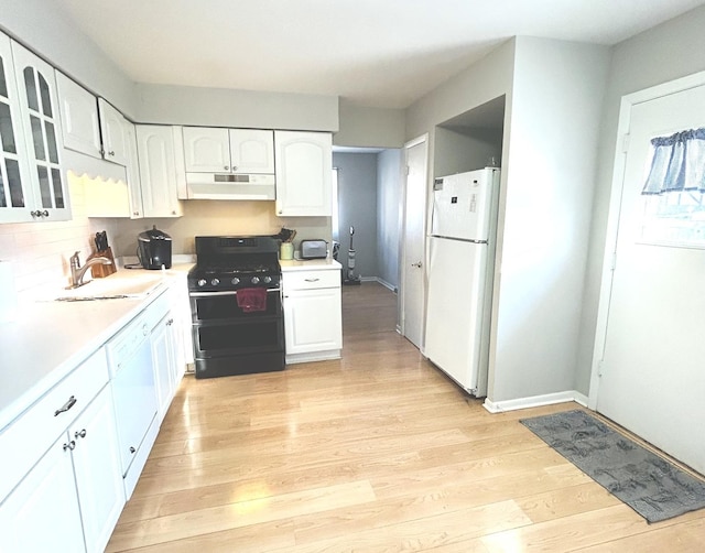 kitchen with black gas range oven, sink, white cabinets, white fridge, and light hardwood / wood-style flooring