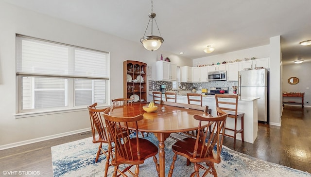 dining room featuring dark wood-style flooring, visible vents, and baseboards