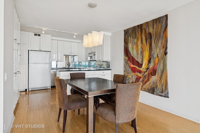 dining space with track lighting, visible vents, and light wood-style floors