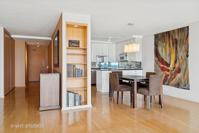 dining room with light wood-style flooring and rail lighting