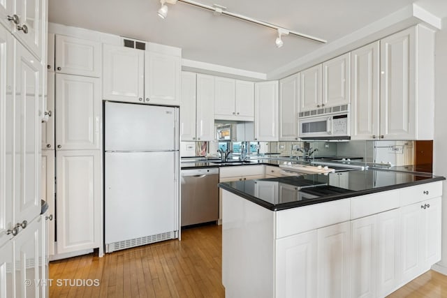 kitchen featuring visible vents, dark countertops, white cabinetry, white appliances, and a peninsula