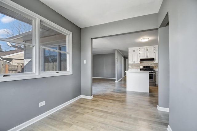 kitchen with backsplash, white cabinetry, stainless steel range, and light wood-type flooring