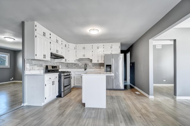 kitchen featuring backsplash, stainless steel appliances, a center island, light hardwood / wood-style floors, and white cabinetry