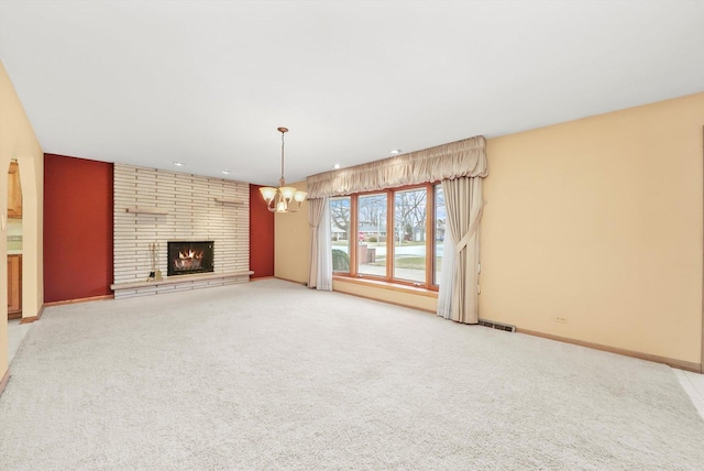 unfurnished living room featuring carpet floors, an inviting chandelier, and a brick fireplace