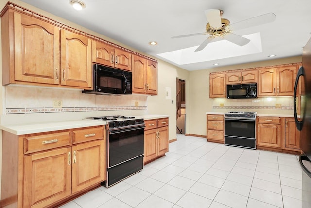 kitchen featuring a skylight, ceiling fan, backsplash, light tile patterned floors, and black appliances