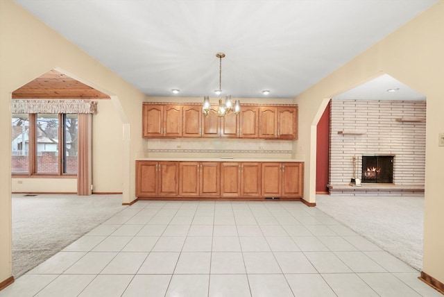 kitchen featuring a chandelier, light carpet, hanging light fixtures, and a brick fireplace