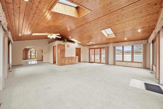 unfurnished living room with a skylight, ceiling fan, wooden ceiling, high vaulted ceiling, and light carpet