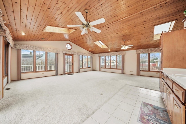 unfurnished living room with a skylight, ceiling fan, light colored carpet, and wood ceiling