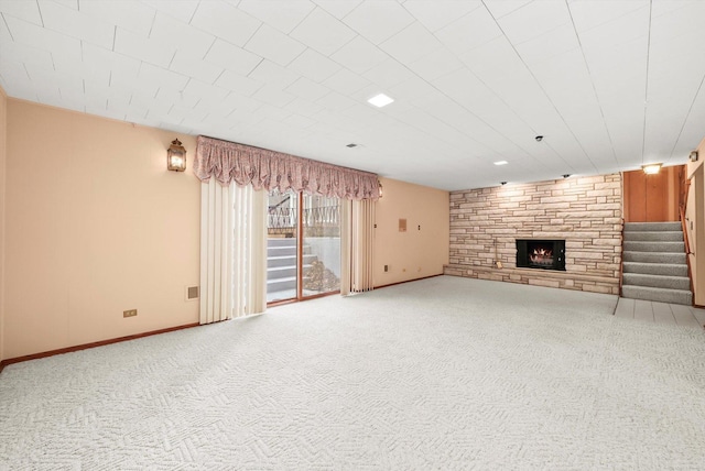 unfurnished living room with a stone fireplace and carpet floors