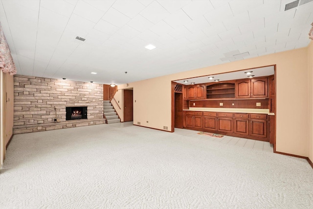 unfurnished living room with a stone fireplace and light colored carpet