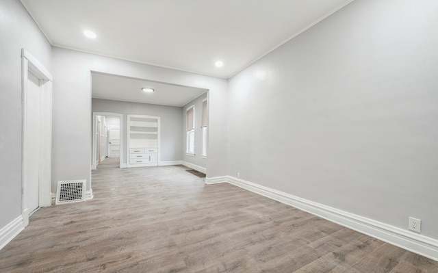 unfurnished living room with wood-type flooring and ornamental molding