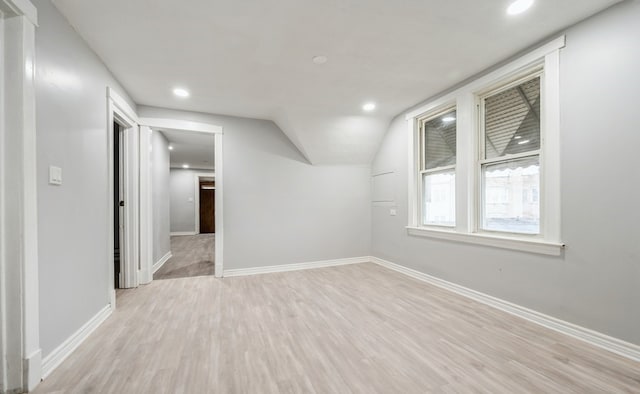 empty room with light hardwood / wood-style flooring and lofted ceiling