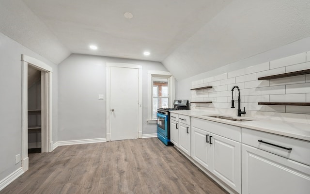 kitchen featuring white cabinets, lofted ceiling, sink, and stainless steel range with gas stovetop