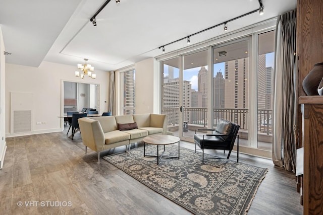 living room with hardwood / wood-style flooring, track lighting, and an inviting chandelier