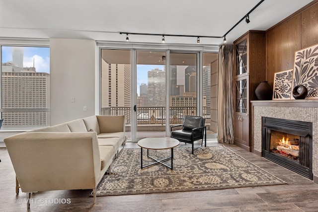 living room with a tile fireplace, track lighting, and hardwood / wood-style flooring