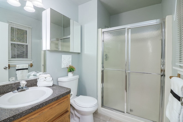 bathroom featuring tile patterned floors, vanity, toilet, and a shower with shower door