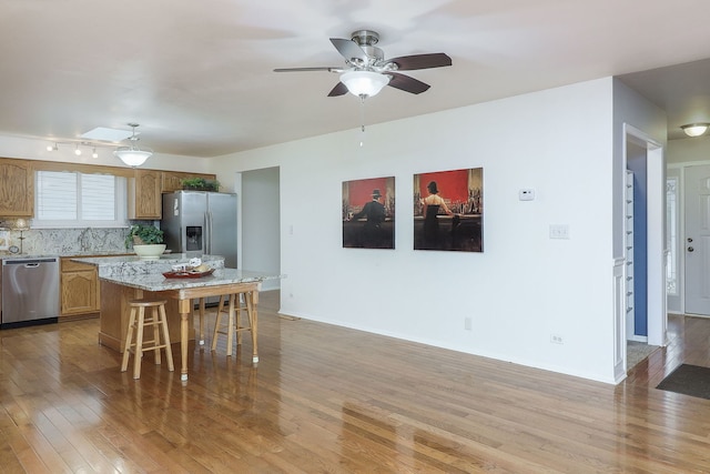 kitchen with tasteful backsplash, light hardwood / wood-style flooring, a breakfast bar, a kitchen island, and appliances with stainless steel finishes