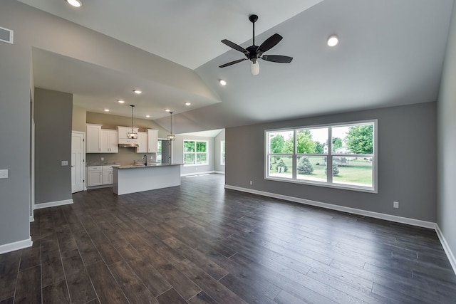 unfurnished living room with dark hardwood / wood-style floors, vaulted ceiling, and ceiling fan