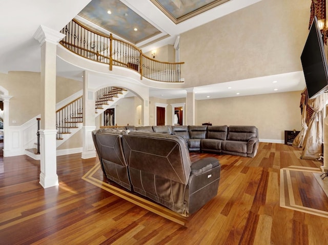 living room featuring stairs, decorative columns, and wood finished floors