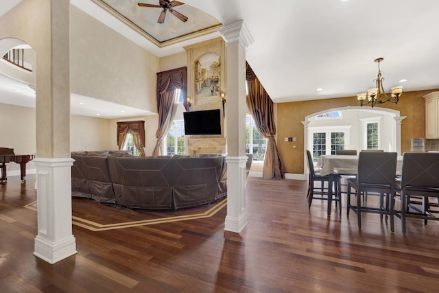 living room featuring decorative columns, baseboards, dark wood-style floors, ceiling fan with notable chandelier, and recessed lighting