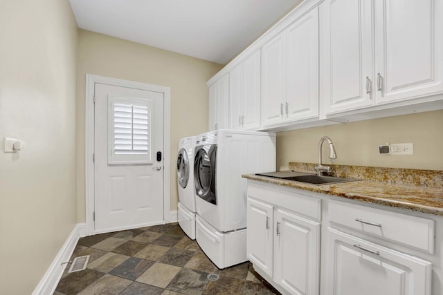 clothes washing area featuring washing machine and dryer, a sink, visible vents, baseboards, and cabinet space