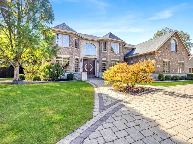 view of front of house with brick siding, a front yard, and a shingled roof