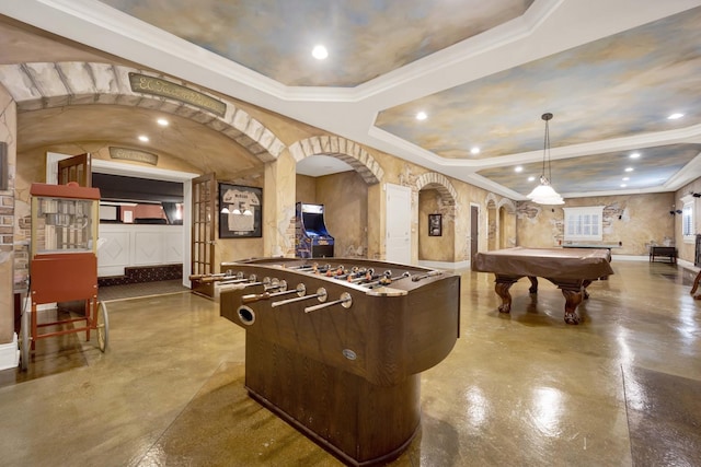 playroom featuring finished concrete flooring, arched walkways, a tray ceiling, and ornamental molding