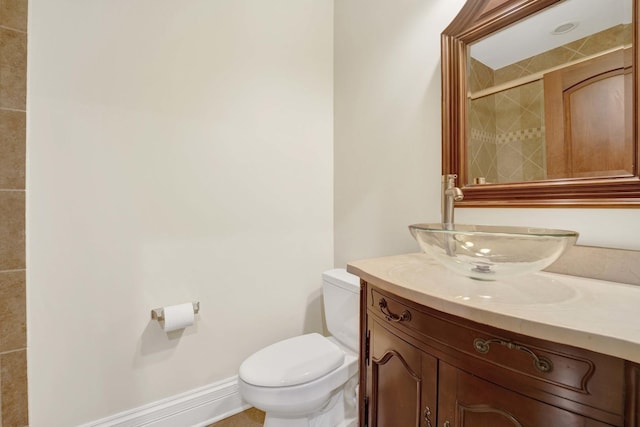 bathroom featuring toilet, baseboards, a tile shower, and vanity