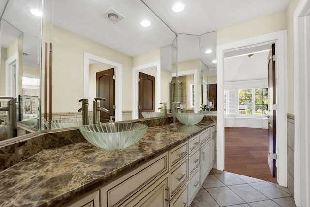 full bathroom featuring double vanity, tile patterned flooring, a sink, and wainscoting