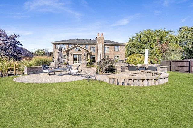 rear view of property featuring a patio area, a chimney, fence, and a lawn