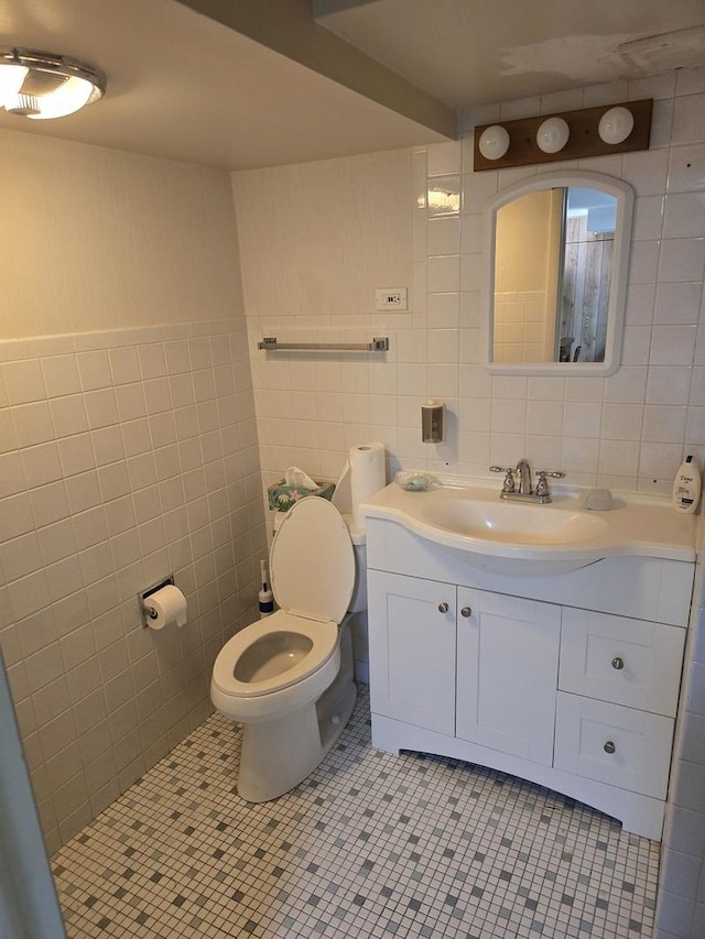 bathroom with tile patterned floors, vanity, toilet, and tile walls