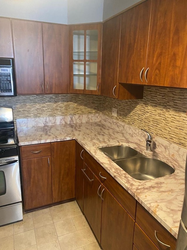 kitchen with sink, stainless steel appliances, tasteful backsplash, light stone counters, and light tile patterned flooring