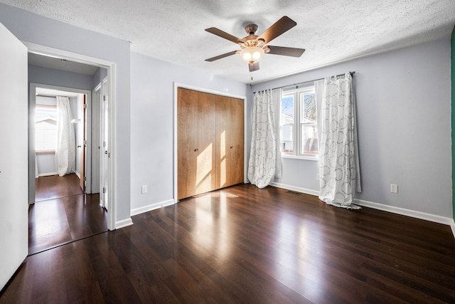 unfurnished bedroom with a textured ceiling, dark hardwood / wood-style flooring, a closet, and ceiling fan