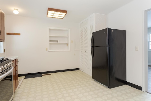 kitchen featuring built in features, black refrigerator, and stainless steel range oven