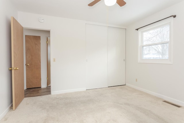 unfurnished bedroom featuring ceiling fan, a closet, and light colored carpet