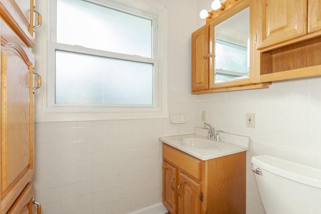 bathroom with vanity, toilet, and tile walls